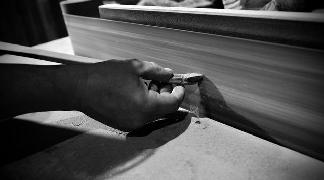 Schwarz-weiß: eine Hand an einem Bogenrohling